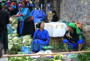 Une dame tay vend des légumes frais au marché de Dong Van